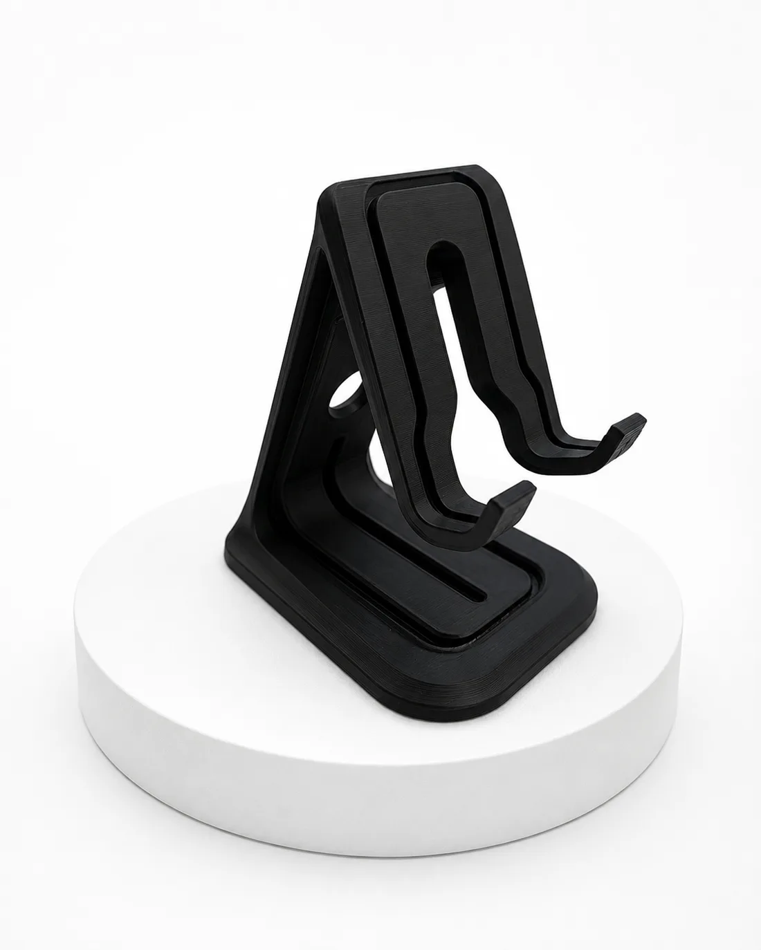 Suporte para celular preto impresso em 3D sobre base branca